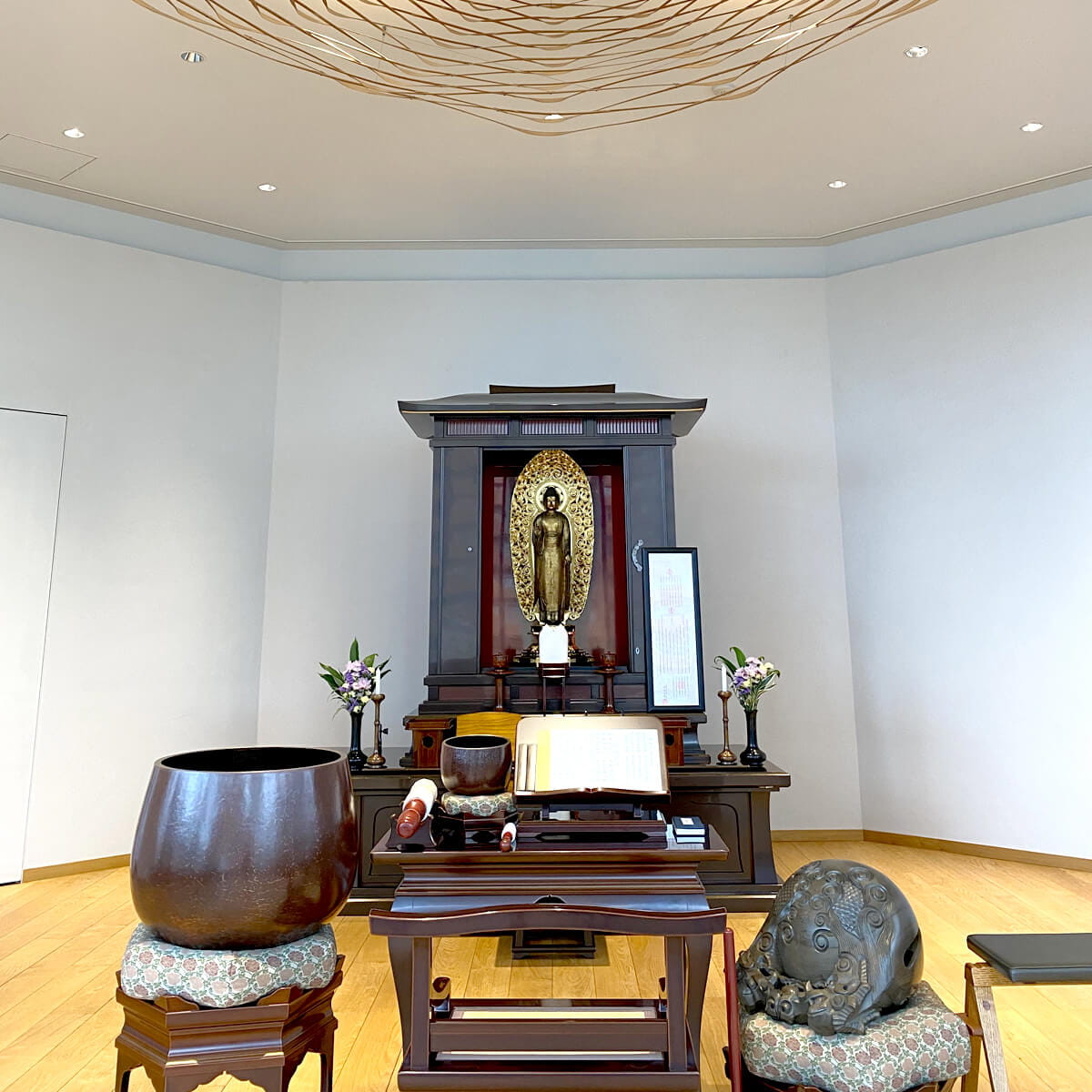 明るい室内の祭壇には金色の仏像が中央に安置されており、周囲には花瓶と供物が飾られている